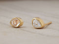 Darian Herk Diamond Bezel Stud Earrings featuring raw Herkimer Diamonds in gold-plated settings on a textured surface.