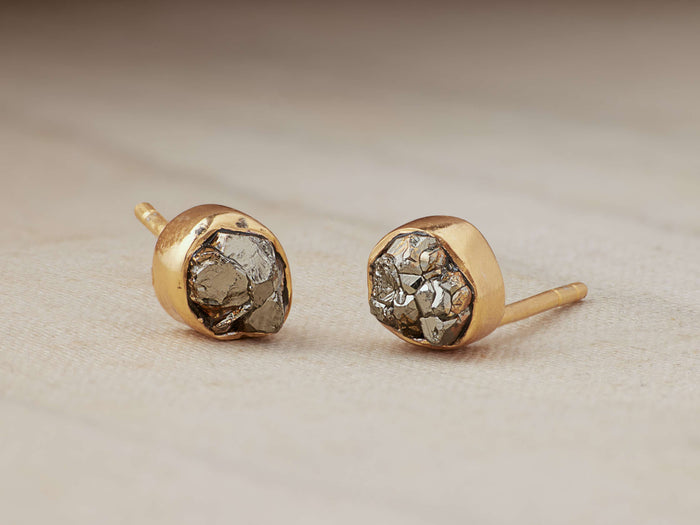 Darian Pyrite Bezel Stud Earrings with irregular pyrite nuggets set in gold-plated sterling silver, placed on a soft surface.