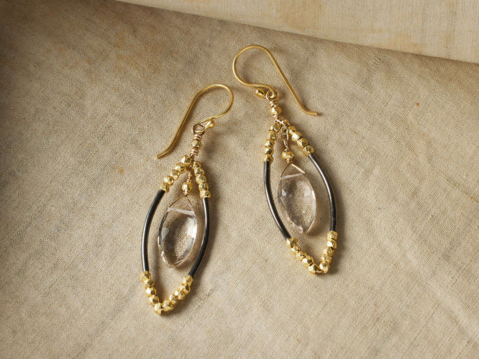 Delphine Earrings with gold vermeil French wire, smoky quartz center, and oxidized silver accents on a beige surface.