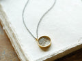 Diamond Shaker Necklace with 18kt gold-plated round pendant, clear glass showing loose diamonds, on a long black chain.