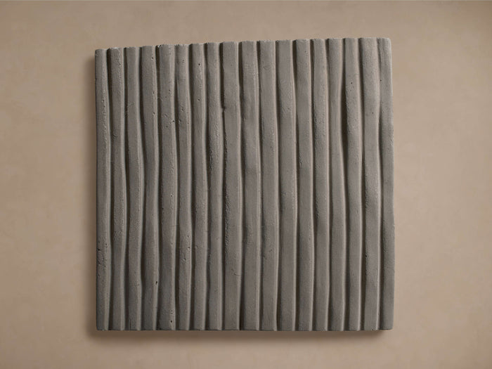 Eden Outdoor Finish Board, a dark gray square panel with vertical wavy ribbed texture, against a light beige wall.