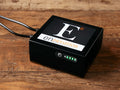 Enouvation E6 Motion Battery Pack on a wooden surface, featuring a black box design with LED indicator lights and cables connected.
