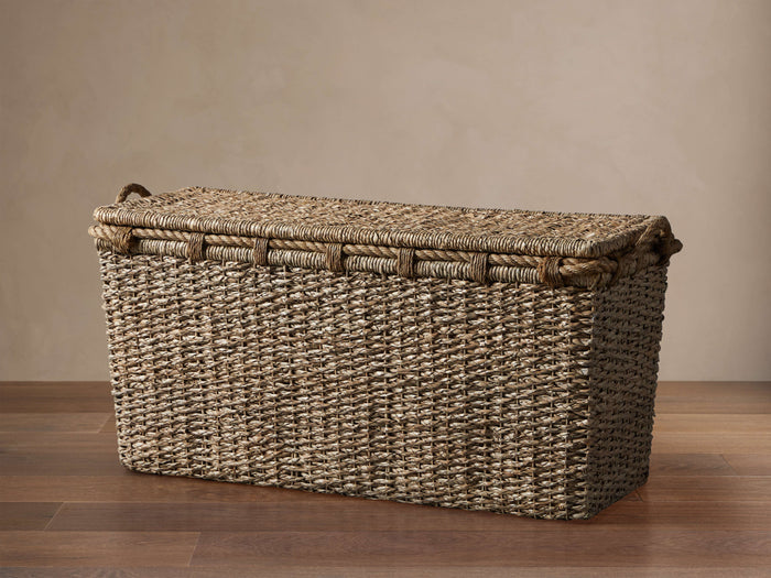 Natural rectangular handwoven seagrass Entry Console Basket with a matching lid and rope trim, on a wood floor.