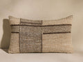 Esencia Herringbone Pillow: rectangular, woven beige & dark brown with geometric herringbone stripes, against a light wall.