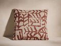 Estella Pillow, square, beige cotton-linen with bold red-brown abstract pattern, upright against a light wall.
