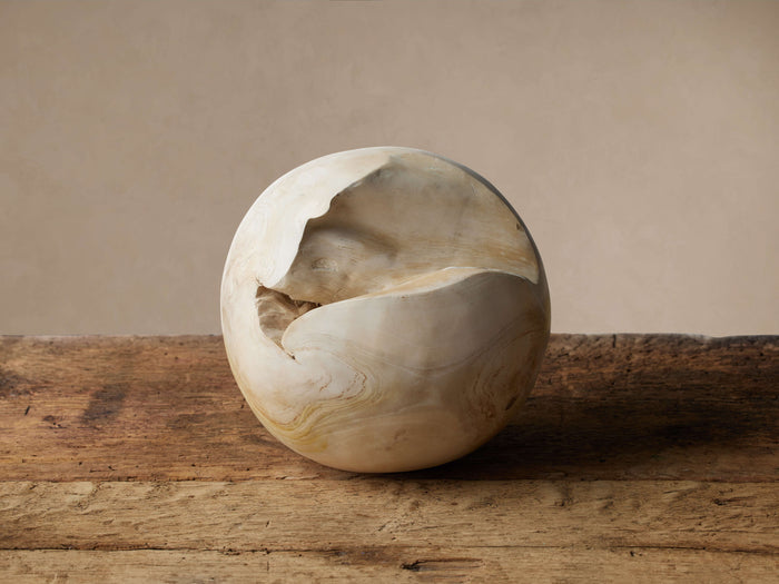 Rustic Etta Sphere, a light natural teak root sphere with an organic opening, sits on a weathered wooden table.
