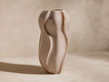 Eva Large Seedpod Vase: a tall, glossy taupe ceramic vase with organic, seedpod-like curves on a light textured surface.