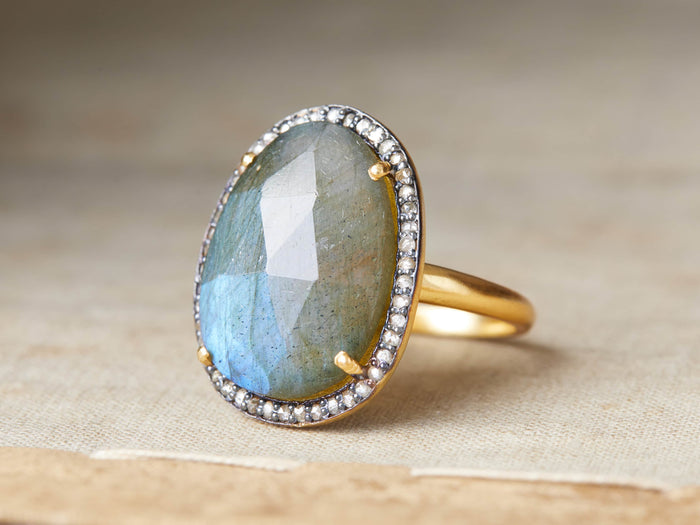 Evelina Labradorite Ring with an oval labradorite stone, surrounded by diamonds, set on a gold and black rhodium plated band.