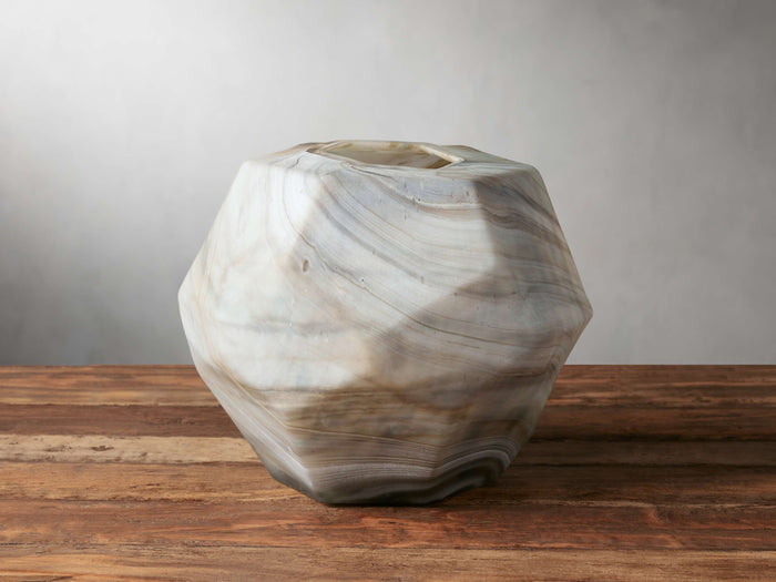 Facet Vase with angular silhouette, swirled beige and gray colors, hand-blown glass on wooden surface, light gray background.