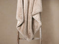 Soft Fairbanks Faux Fur Throw in Dune, a light beige blanket, draped over a wooden ladder, showing plush texture and microfiber lining.
