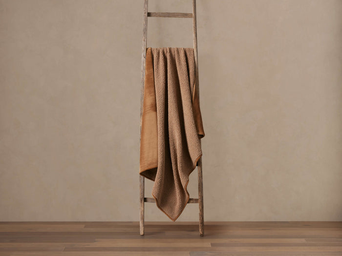 Warm brown Faux Fur Sherpa Throw draped over a wooden ladder, showing soft fur and textured sherpa sides.