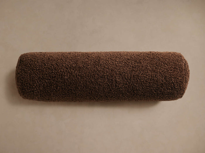 Horizontal dark brown Faux Sherpa Bolster Pillow, cylindrical, with plush, textured faux fur on a light tan background.