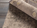 Felted Rug Pad under a patterned rug, showing its grey felt texture and no-slip rubber backing. The rug corner is lifted.