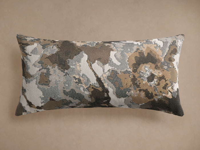 Flora Lumbar Pillow with an abstract floral pattern in brown, beige, gray, and white, lying horizontally on a plain background.