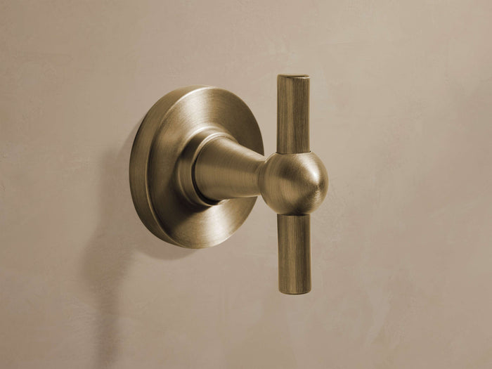 Fulton Robe Hook in antique brass finish, mounted on a wall. Features a circular base with a horizontal cylindrical hook.