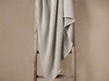 Mist-colored garment-dyed throw with waffle pattern, casually draped over a rustic wooden ladder against a neutral wall.