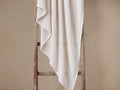 White Garment-Dyed Throw with luxurious waffle pattern draped softly over a rustic wooden ladder.