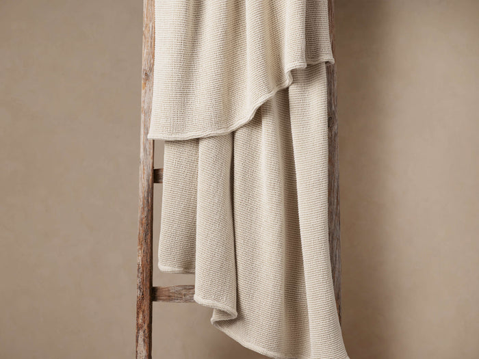 Light beige Garment-Dyed Throw with waffle texture draped over a rustic wooden ladder against a warm, neutral wall.