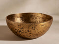 Harper Bowl: A decorative, round, brass-finished aluminum bowl with a distressed, hammered texture, shown slightly from above.