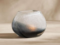 Indigo Tealight Holder. Round, crackled glass with frosted white fading to deep indigo. Warm glow inside on a light surface.