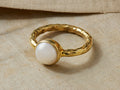 Isar Ring: Hammered 14kt gold vermeil ring featuring a prominent white freshwater pearl, resting on a light beige textile.