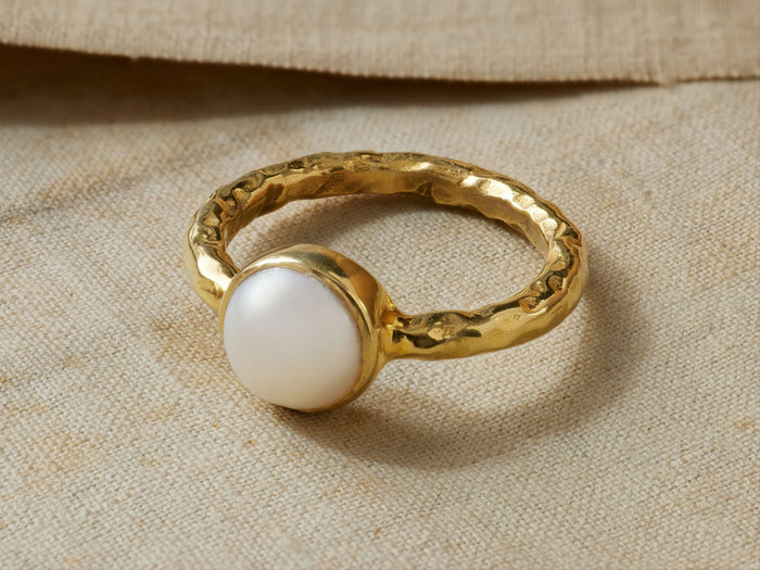 Isar Ring: Hammered 14kt gold vermeil ring featuring a prominent white freshwater pearl, resting on a light beige textile.