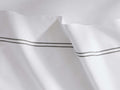 White Italian Embroidered Percale Flat Sheet, draped with two parallel dark grey embroidered lines on the border.