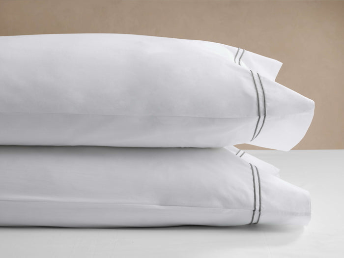 Two white Italian Embroidered Percale Pillowcases, stacked. Each features two thin gray embroidered lines on the border.