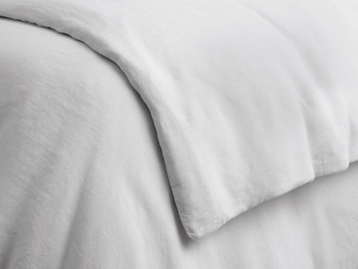 Close-up of a light gray Italian garment-dyed linen duvet, draped with soft folds, highlighting its natural, breathable texture.