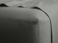 Close-up of a charcoal grey Italian garment-dyed linen fitted sheet on a mattress, highlighting its texture and corner detail.