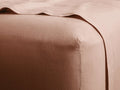 Italian Garment-Dyed Linen Fitted Sheet in a soft pink hue, wrapped tightly around a mattress corner. The fabric shows a smooth, slightly textured finish.