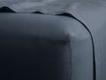 Deep blue-grey Italian Garment-Dyed Linen Fitted Sheet, showing a fitted corner on a mattress with a draped sheet.