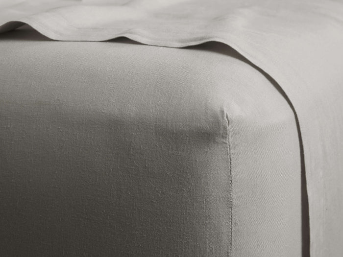 Light grey Italian garment-dyed linen fitted sheet, showcasing its soft, subtly wrinkled texture and a neatly tailored corner.