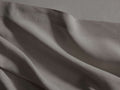 Close-up of a draped Italian Garment-Dyed Linen Flat Sheet in mink, showing soft folds and textured fabric with a hem.