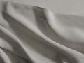 Draped grey Italian Garment-Dyed Linen Flat Sheet with soft, natural folds and a visible top hem, showcasing its texture.