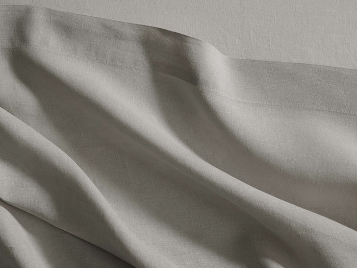 Draped grey Italian Garment-Dyed Linen Flat Sheet with soft, natural folds and a visible top hem, showcasing its texture.