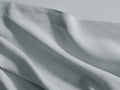 Soft light blue-grey Italian Garment-Dyed Linen Flat Sheet, draped with casual folds and a visible stitched hem.