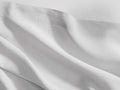 Close-up of white Italian Garment-Dyed Linen Flat Sheet, draped with soft folds, showing its natural texture & hem.