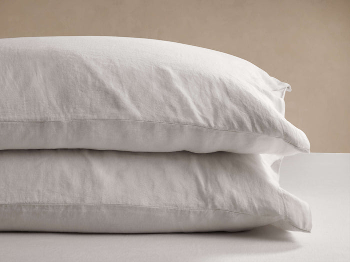 Two natural Italian Garment-Dyed Linen Pillowcases stacked horizontally, showing soft, wrinkled texture against a beige background.