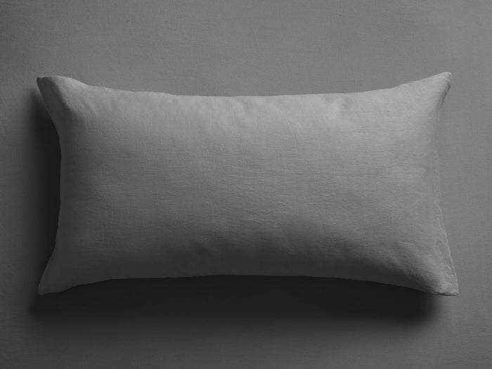 Horizontal charcoal Italian garment-dyed linen sham with visible texture, lying on a dark gray surface, casting a soft shadow.