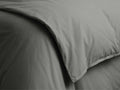Close-up of a charcoal Italian Garment-Dyed Percale Duvet, showing its soft, draped fabric and a finely stitched hem.