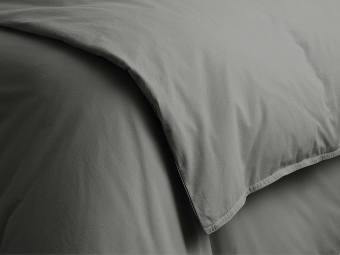 Close-up of a charcoal Italian Garment-Dyed Percale Duvet, showing its soft, draped fabric and a finely stitched hem.