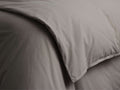 Close-up of a folded Italian Garment-Dyed Percale Duvet in soft taupe/grey, highlighting its smooth, naturally textured fabric.