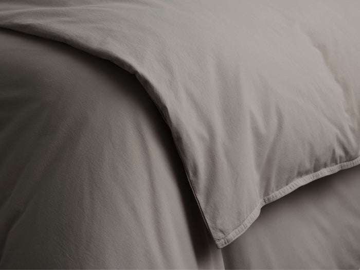 Close-up of a folded Italian Garment-Dyed Percale Duvet in soft taupe/grey, highlighting its smooth, naturally textured fabric.