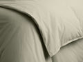 Close-up of a light greenish-beige Italian Garment-Dyed Percale Duvet, with gentle folds and a visible hemmed edge.