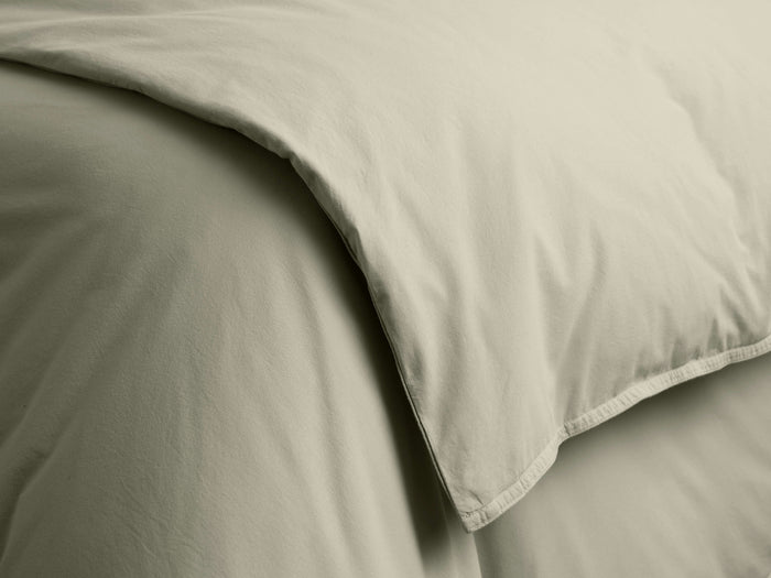 Close-up of a light greenish-beige Italian Garment-Dyed Percale Duvet, with gentle folds and a visible hemmed edge.