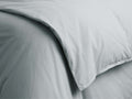 Close-up of a sky blue Italian garment-dyed percale duvet, showing a gentle fold, soft texture, and subtle creases.