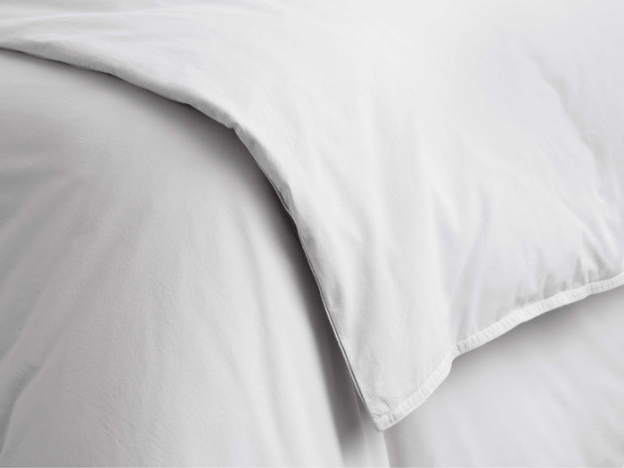 Close-up of a white Italian Garment-Dyed Percale Duvet, softly folded with natural creases, highlighting its relaxed texture.