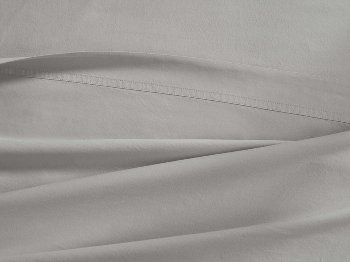 Light gray Italian Garment-Dyed Percale Flat Sheet, gently folded, revealing its soft texture and prominent top hem.