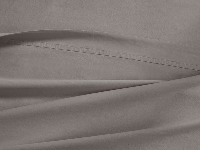 Close-up of a light gray Italian Garment-Dyed Percale Flat Sheet, draped with soft folds and a visible stitched hem.